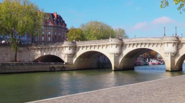 Güneşli bir sonbahar gününde Paris 'teki Seine Nehri' ni tekneler ve tarihi binalarla geçen Pont Neuf köprüsünün manzarası. Paris, Fransa - 11 Ekim 2025.
