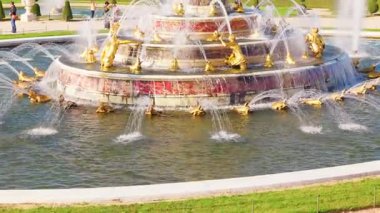 Arka planda güçlü su jetleri ve Versailles Sarayı olan büyük bir çeşmenin manzarası, ikonik Fransız simgesi. Versailles, Fransa - 12 Ekim 2025.