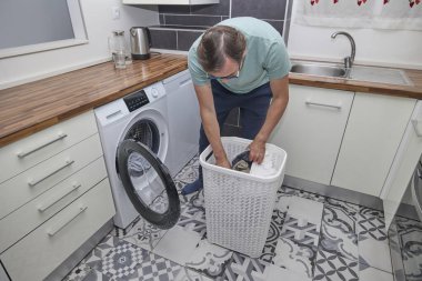 Modern mutfakta çamaşır yıkayan bir adam..