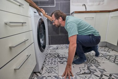 Modern mutfakta çamaşır yıkayan bir adam..