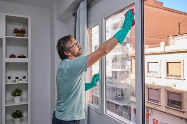 Sünger ve spreyle evde cam temizliği.