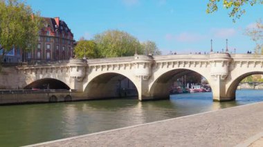 Güneşli bir sonbahar gününde Paris 'teki Seine Nehri' ni tekneler ve tarihi binalarla geçen Pont Neuf köprüsünün manzarası. Paris, Fransa - 11 Ekim 2025.