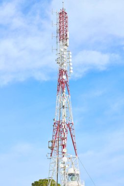 Antenli ve çanaklı kırmızı ve beyaz iletişim kulesi.