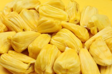 Parlak bir arkaplanda düzgün yerleştirilmiş taze sarı Jack meyvesi görüntüsü. Canlı sarı renk ve sulu doku tropikal tatlılığı vurgular. .