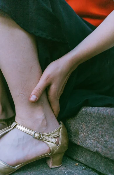 A young woman holding hand on gold dance shoes