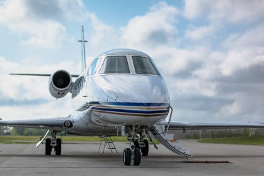 Q-white 'ın üçüncü çeyreğinde küçük bir şirket jeti var. Biniş merdivenleri genişletilmiş. Arka planda bulutlu mavi gökyüzü.