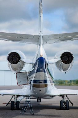 Önlüğün üzerinde bir iş jeti, hem jet motorlarını, hem iniş takımlarını, hem de yerde küçük bir merdivenle kargo kapağını gösteriyor. Simetrik olarak çerçevelenmiş.