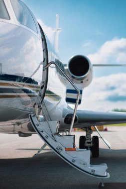 Küçük bir havaalanının pistine park edilmiş küçük bir özel jetin iniş merdivenlerine odaklan..