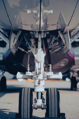 İniş takımları açık olan iniş takımları ve tekerlek montajı yakın plan. Yerden çekilmiş, detaylı uçak şasisi görünüyor..