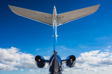 Çift motorlu jet kuyruk bölümünün düşük açılı arka görüntüsü ve orta ölçekli bir iş jetinin yatay dengeleyicisi. Gökyüzü ve bulutlarla geniş açı bileşimi.