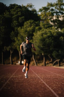 Koşu antrenmanı sırasında hızlı koşan erkek sporcu formda ve aktif kalıyor.
