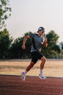 Erkek sporcu, yoğun atletizm antrenmanında hızlı koşuyor.