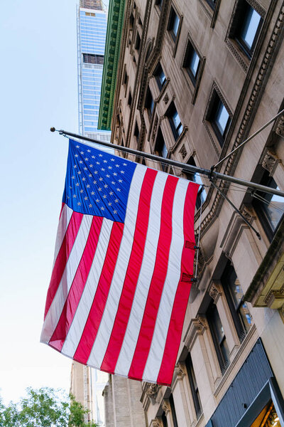 Американский флаг вывешивается из исторического здания в финансовом районе Нью-Йорка