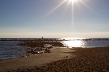 Sakin deniz dalgaları açık mavi gökyüzünün altında kumlu sahilde