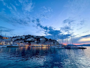 Günbatımında Hydra Limanı 'nda deniz feneriyle demirlenmiş yatlar.