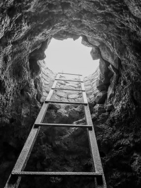 Karanlık mağaradan aydınlığa çıkan metal merdiven.