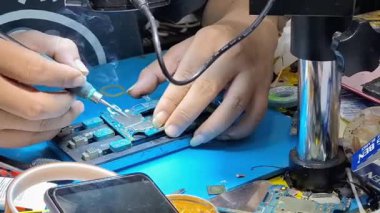 Jakarta Endonezya -7 Ağustos 2025: Bir teknisyen tarafından lehimleme ya da sabit tahtanın parçalarının değiştirilmesi gibi karmaşık işler için özel araçlar kullanan bir dahili telefon bileşenlerinin yakın çekimi