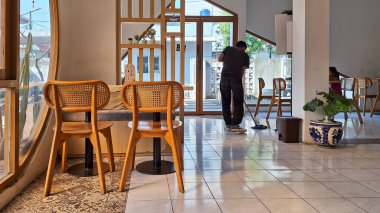Tangerang Endonezya - 23 Haziran 2024: Temu kahvesinin zeminini temizleyen işçilerin olduğu bir kahve dükkanı. Modern minimal kafe iç tasarımı.