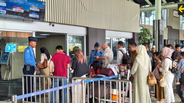 Jakarta Endonezya - 2 Haziran 2024: Soekarno hatta uluslararası havaalanındaki giriş ve çıkış kapısında kimlik ve bilet gibi yolcu taşımacılığı belgelerini kontrol eden havaalanı görevlisi.