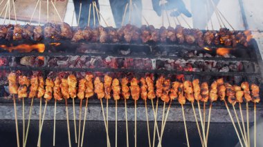 Satay (veya sate), bir adam tarafından mangal kömürü üzerinde kızartılan ve ete belirgin dumanlı bir tat veren, baharatlı, bambu çubuğunda şişlenmiş, popüler bir Güneydoğu Asya yemeği. Üst Görünüm.