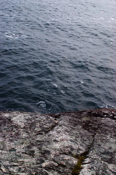 Koyu mavi su kayalık kıyı şeridine karşı