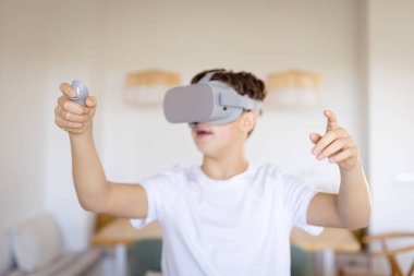 Sanal gerçeklikle oynayan genç, sola bakıyor, evde bir vr kulaklık ve kontrolörle el kol hareketi yapıyor.