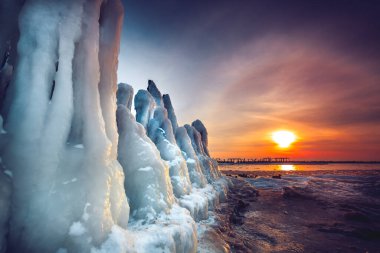 Litvanya 'nın Baltık Denizi kıyısındaki eski iskelenin kalıntıları üzerine dondurulmuş gün batımı