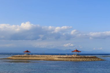Balis 'in sakin bir kıyı şeridi manzarası, dağ arka planında manzaralı pavyonlar.