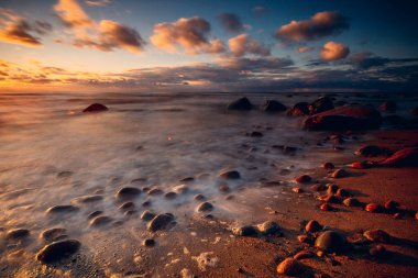 Kayalık bir sahilde, Litvanya 'da dalgaların üzerinde kasvetli bir gün batımı 