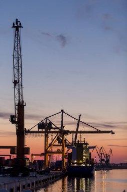 Günbatımında Klaipeda Limanı kargo gemileri ve endüstriyel vinçlerle, Litvanya