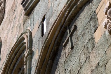 Gotik kemerli ve yıpranmış taş duvar maskesine çapraz gölgeli tarihi kilise dış görünüşü.