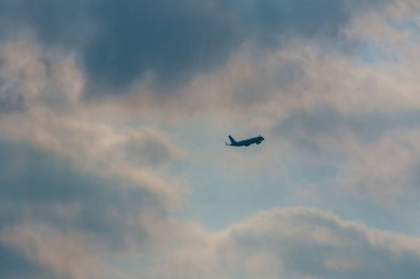 Bir yolcu uçağı silueti alacakaranlıkta yumuşak pastel bulutlarda süzülür, seyahat, özgürlük ve sessiz bir yolculuk çağrıştırır. Minimum bileşim, geniş gökyüzünün ve sakin, atmosferik seyahat havasını vurgular..