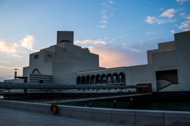 Katar 'ın Doha kentindeki İslam Sanatları Müzesi, gün batımında limana yansıyarak I. M. Pei tarafından tasarlanan ikonik geometrik mimariyi sergiliyor..