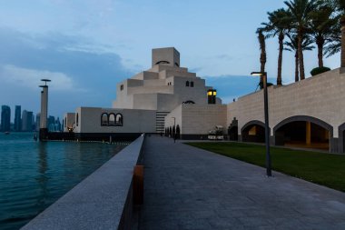 Katar 'ın Doha kentindeki İslam Sanatları Müzesi, gün batımında limana yansıyarak I. M. Pei tarafından tasarlanan ikonik geometrik mimariyi sergiliyor..