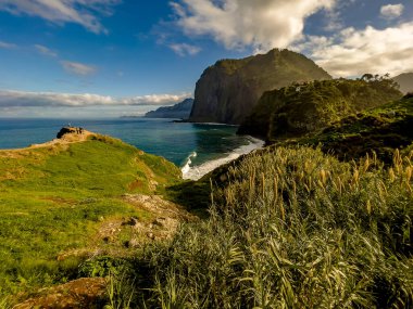 Madeira Adaları 'nın panoramik manzarası sarp yeşil dağlar, sahil kayalıkları, küçük yamaç köyleri ve dramatik bulutlu bir gökyüzü altında Atlantik Okyanusu' nun dalgaları ile engebeli kuzey sahilleri..