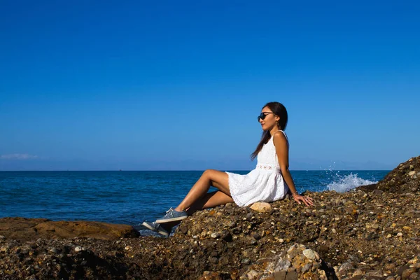 Güneşli bir günde Sahildeki Kayalıklarda Beyaz Elbiseli Kadın pozu