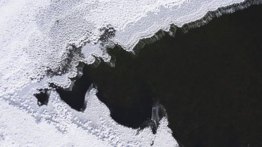 Beyaz kar ve koyu donmuş su arasındaki zıtlığın yukarıdan aşağıya doğru görüntüsü