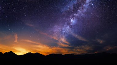 Galaksi gece arkaplanı yıldızların altındaki bir dağın üzerinde, masaüstü duvar kağıdı veya görsel proje için günbatımında 4k evren manzarası