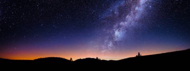 Samanyolu Galaksisi ve yıldızlı gökyüzü gün batımında bir manzara gölgesi üzerinde, masaüstü duvar kâğıdı veya afiş için soğuk gece görüşü geniş arka plan