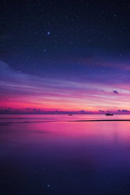 Gün batımında yıldızlı gökyüzünü yansıtan bir gölün üzerinde 4k pembe ve mor gün batımı, telefon arkaplanı için güzel bir duvar kağıdı ya da görsel