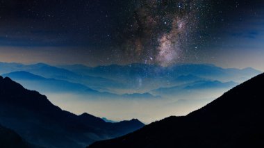Galaksi ve yıldızlı gece gökyüzü mavi saat alacakaranlığında bir dağ gölgesi üzerinde, 4k doğa ve evren masaüstü veya web arkaplanı için manzara