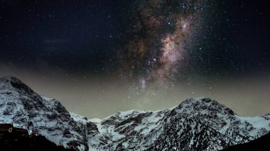Galaksinin arka planında, yıldızlı bir gecede, bir kar dağının üzerinde, sakin bir doğa manzarası duvar kağıdı.