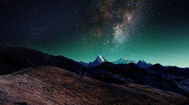 Galaksi ve yıldızlı geceyle birlikte gün batımından sonra parlayan bir sıradağda, 4k evrenin arka planında