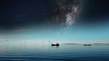 Galaksinin altında sakin bir denizde, yıldızlı bir gecede, eğimli gökyüzü ile, kozmik manzarayı rahatlatır.