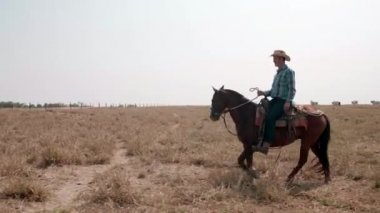 Kovboy çayırda at sürüyor.