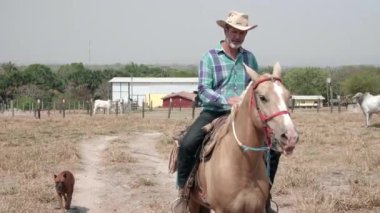 Ağır çekim, yanında köpeğiyle ata binen Kovboy.