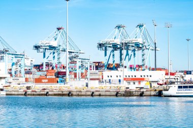 11 Kasım 2025, Algeciras, İspanya: Konteynır ve rıhtım manzarası. Liman boyunca istiflenmiş konteynırlar, vinçler ve küçük tekneler için CEPSA yakıt istasyonu gösteriliyor.