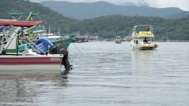 4K 'lık Paratys manzaralı körfez çekimi, renkli demirli teknelerin arasında bir turist botu manevra yapıyor. Atlantik Ormanı ve dağlar çarpıcı bir zemin hazırlıyor..