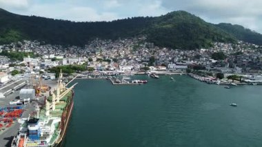 Angra Dos Reis, Brezilya, 13 Ocak 2025: Angra dos Reis 'in limana demirlemiş bir konteynır gemisi, karakteristik dağlar ve şehrin arkasındaki Atlantik Ormanı ile daire çizen insansız hava aracı görüntüsü