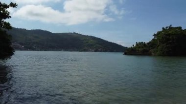 Brezilya 'daki Angra dos Reis' ten insansız hava aracı dağlık ve yağmur ormanı kıyı şeridine doğru uçarken sığ sularda çekilmiş görüntüler.